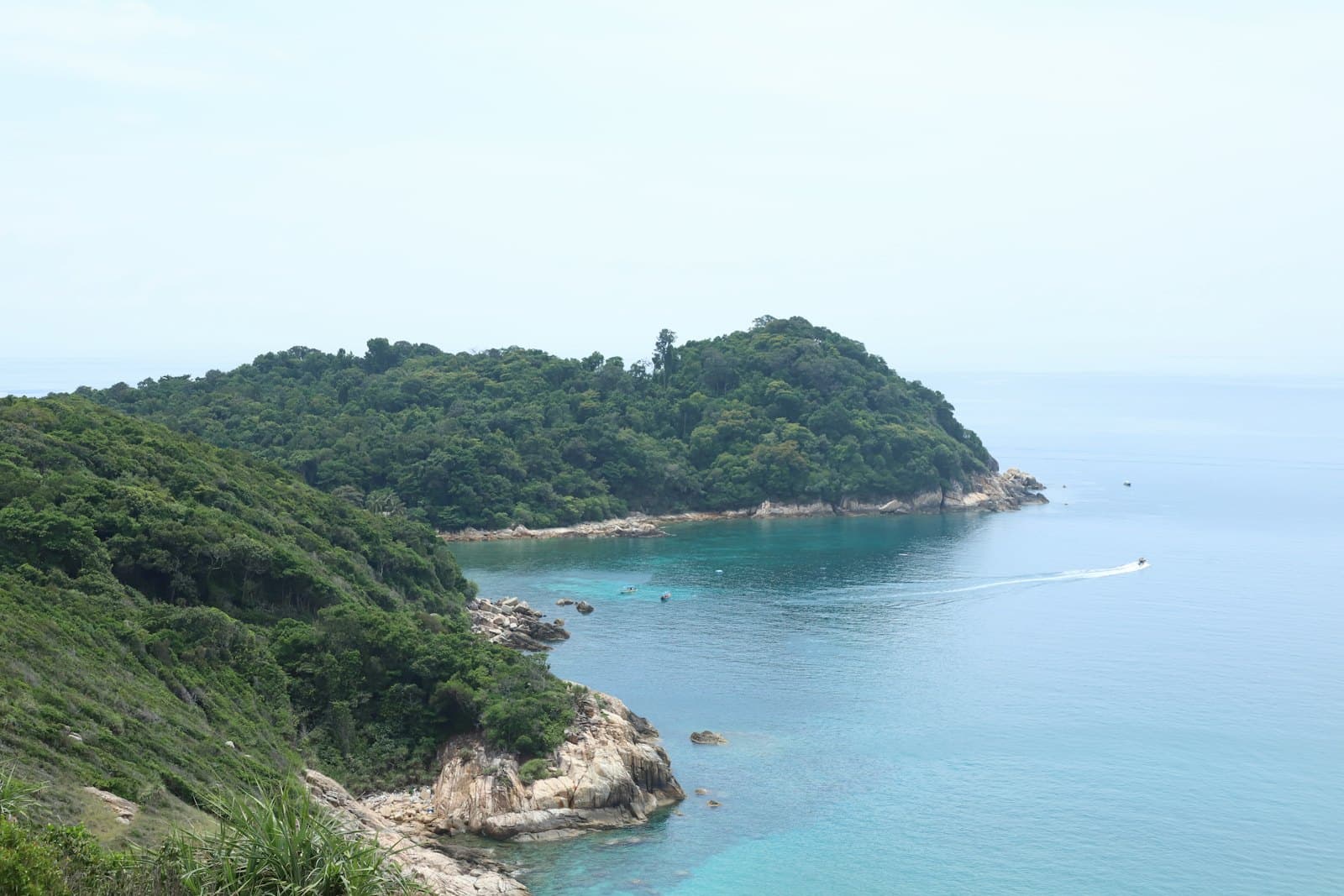 A small boat crossing clear water between two green islands