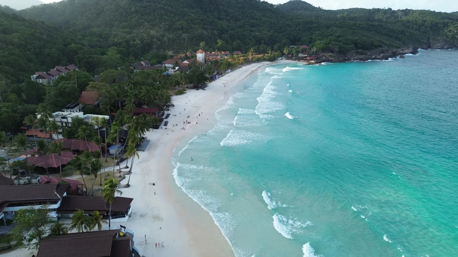 An aerial view of a Redang bay with white sand, turquoise water and jungle-clad hills